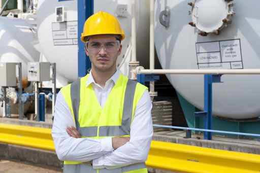 An engineer wearing a hard hat in front of a piece of equipment